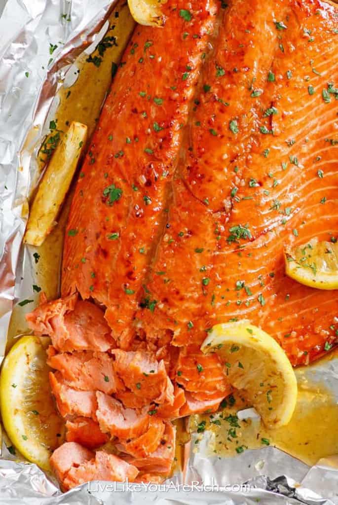 Salmon filet with some pulled apart with lemon wedges and herbs