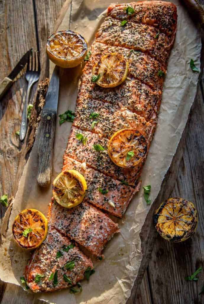 Sliced salmon on butcher paper and grilled lemon slices 