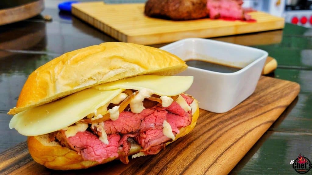 French Dip sandwich on wood board with ramekin of au jus dip 