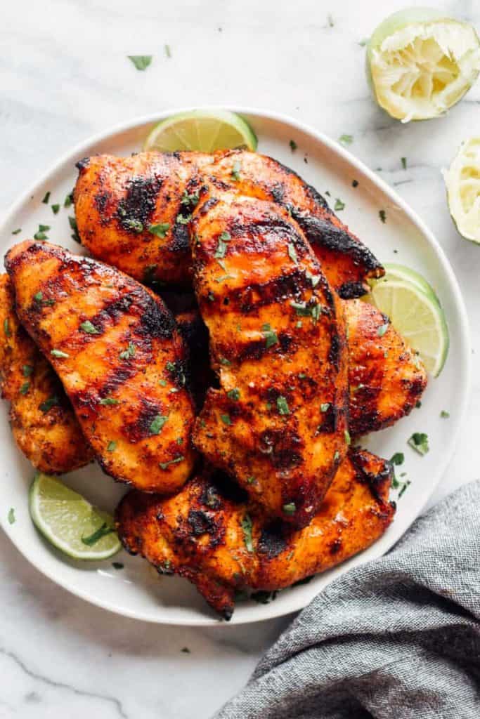 Grilled chicken on white plate with sliced limes 