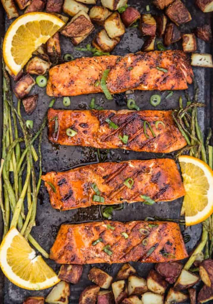 Sliced grilled salmon with asparagus and lemon wedges 