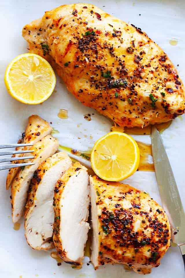 Slicked grilled chicken breasts with sliced lemons
