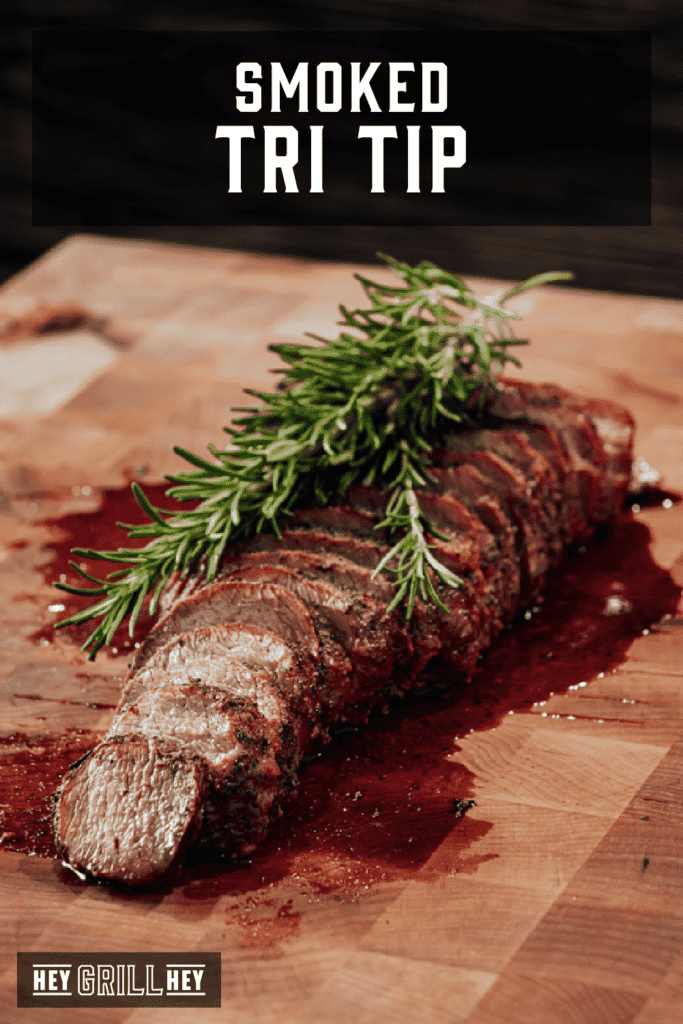 Slicked tri tip on cutting board with herbs