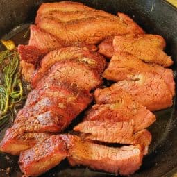 Smoked tri tip roast in cast iron pan with rosemary and garlic