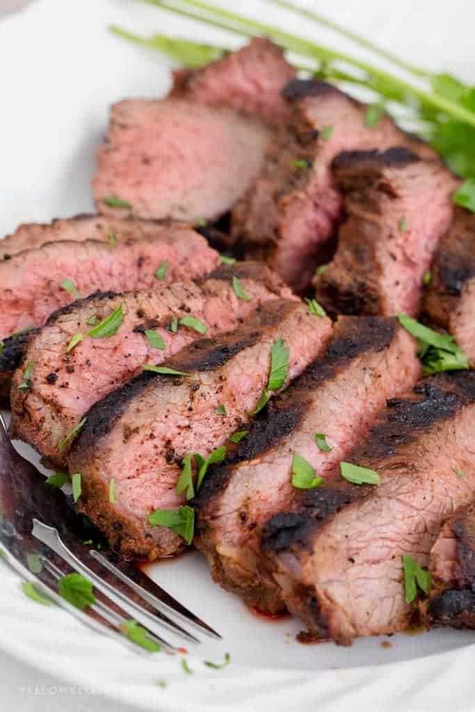 Carved roast on white plate with herbs