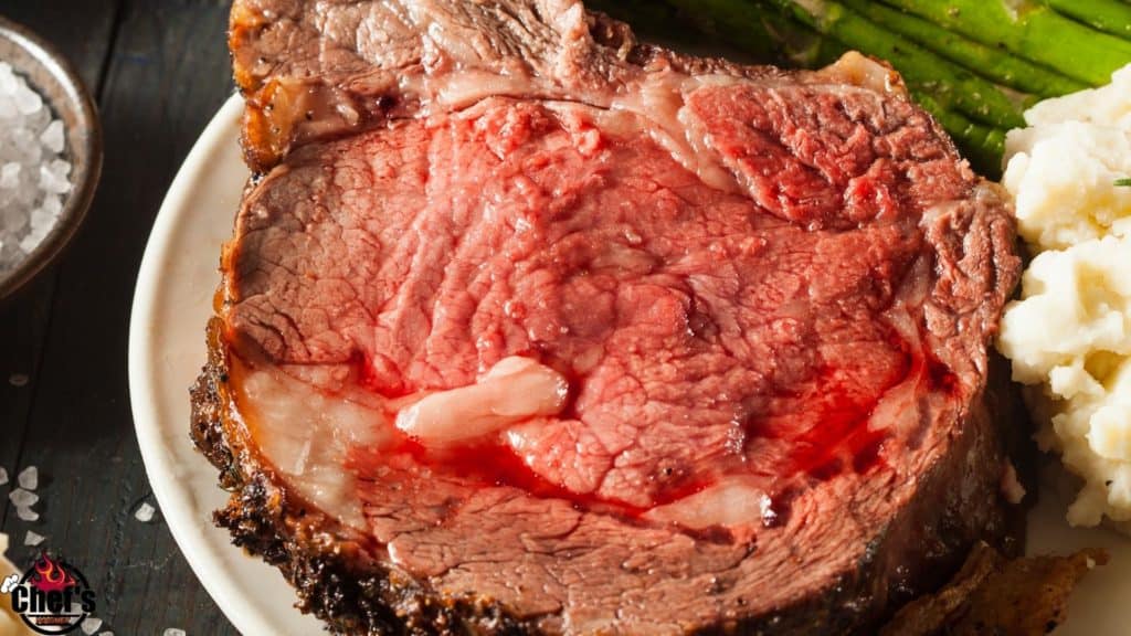 Sliced rare to medium-rare rib roast on a white plate with asparagus 