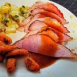Sliced ham with sauce carrots and potatoes