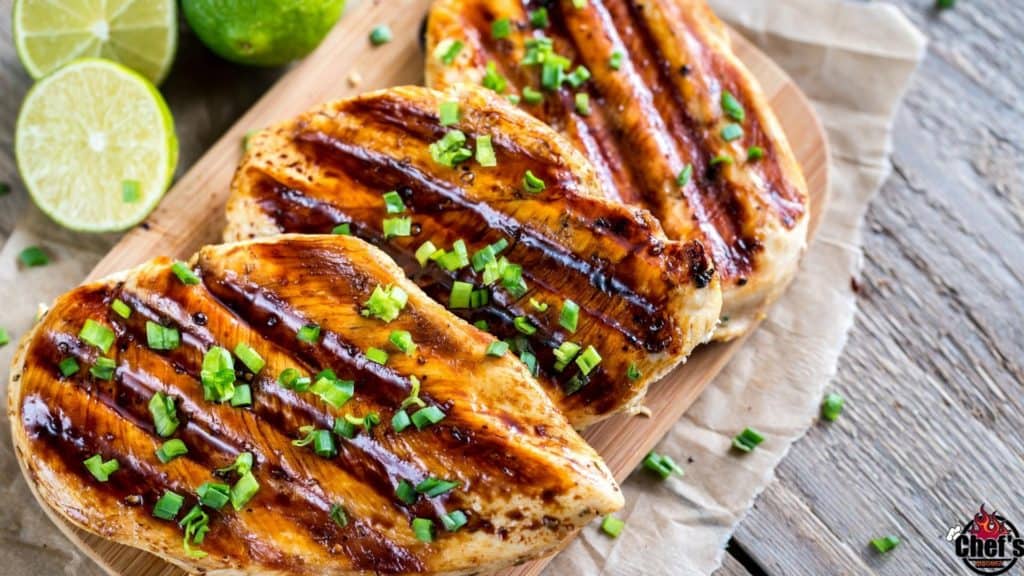 Grilled chicken breasts on cutting board with chopped green onions