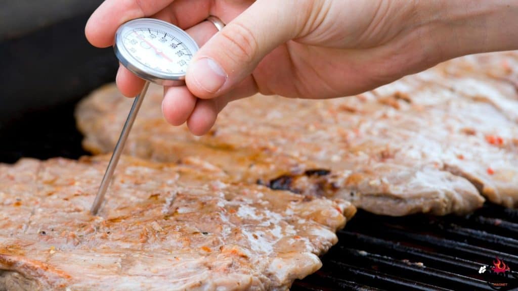 Thermometer in chicken breasts on grill grates